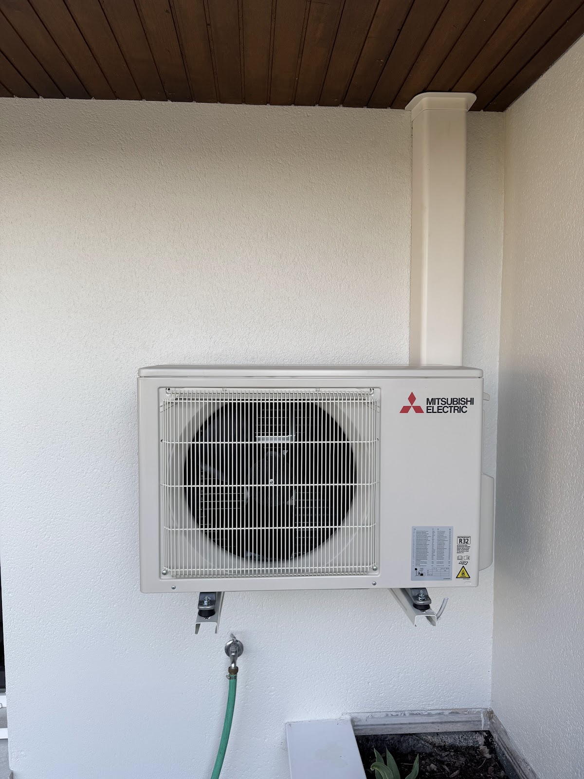 Unité extérieure Mitsubishi Electric installée proprement sous une avancée de toit