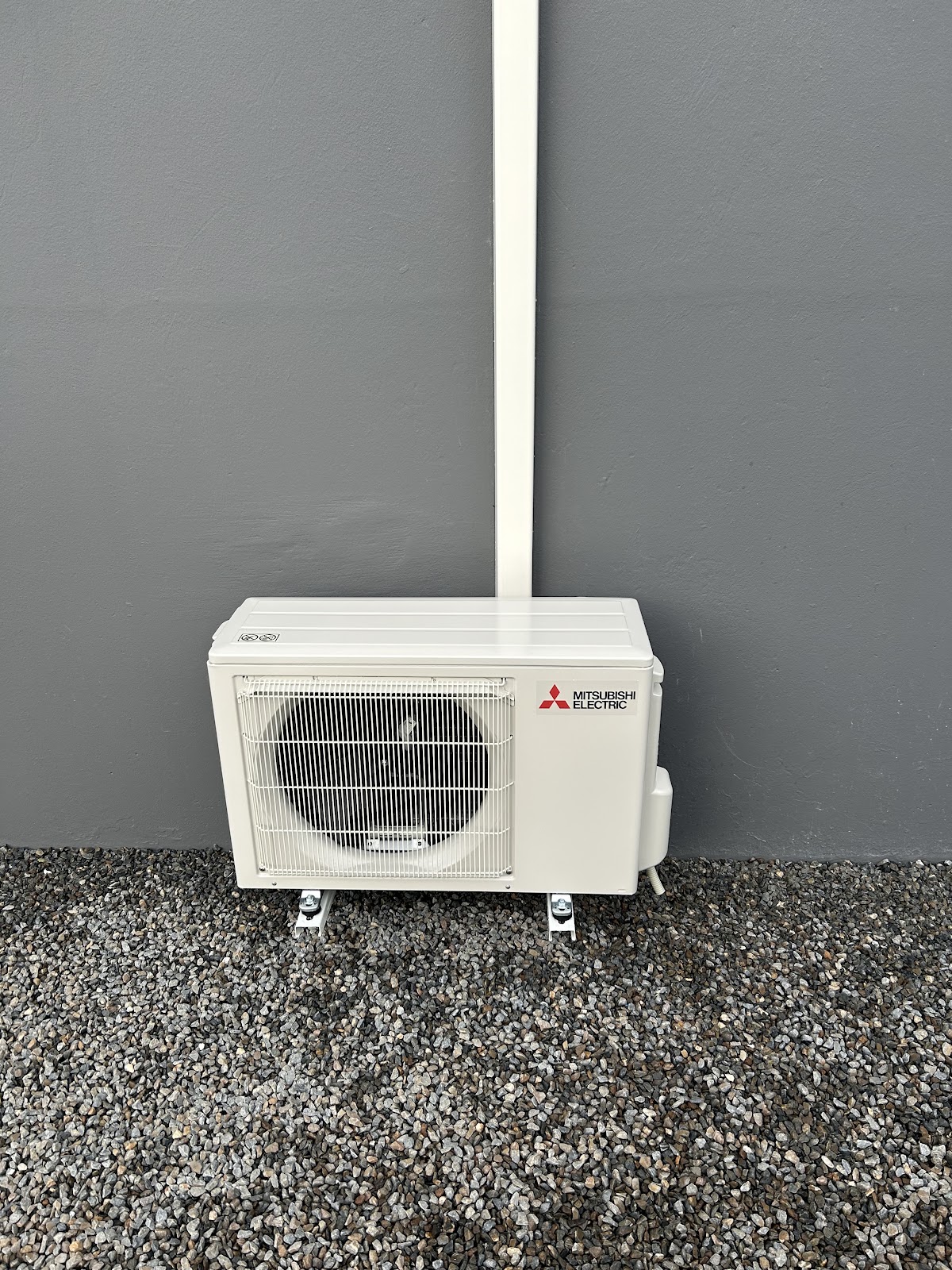 Unité extérieure Mitsubishi Electric posée au sol sur gravier